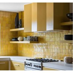 a kitchen with yellow tiles on the wall and shelves above the stove, along with white counter tops