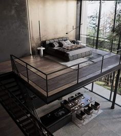 a bed sitting on top of a wooden floor next to a stair case in a living room