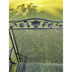 a metal bench with flowers on it in the grass