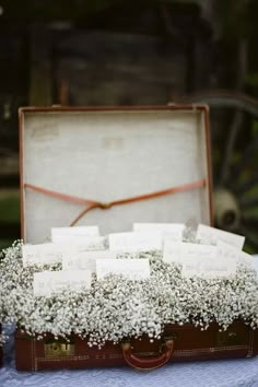 an old suitcase with baby's breath flowers in it is sitting on a table