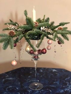 a glass vase filled with christmas decorations on top of a blue tablecloth covered table