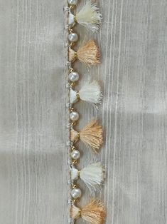 some tassels and beads are hanging on a piece of white fabric with gold trim