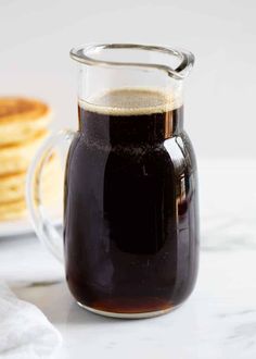 a pitcher filled with liquid sitting on top of a table next to some waffles