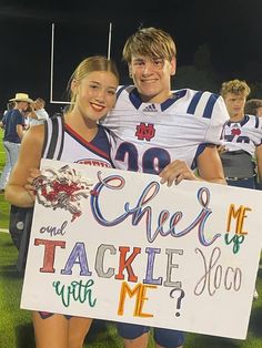 two people holding a sign that says cheer my tackle up with me? on the field