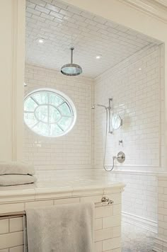 a bathroom with white tiles and a round window