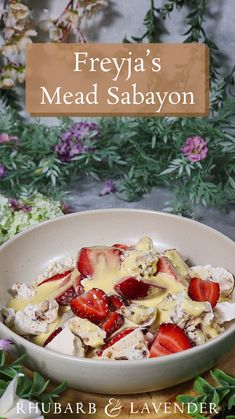 a bowl filled with strawberries and cheese on top of a wooden table next to flowers