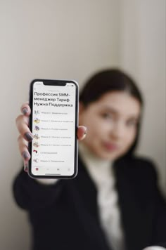 a woman holding up a cell phone in front of her face and showing it to the camera