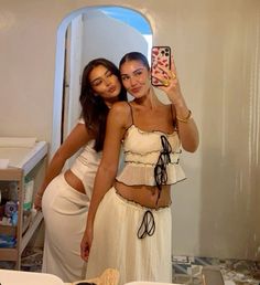 two women taking a selfie in front of a mirror