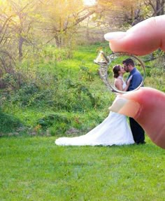 a hand holding a ring with a bride and groom kissing in the middle of it