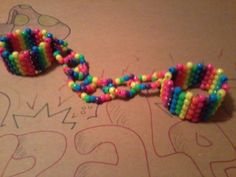 two bracelets made out of beads sitting on top of a piece of craft paper