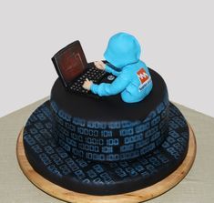 a cake with a laptop on top of it and a blue man in the middle