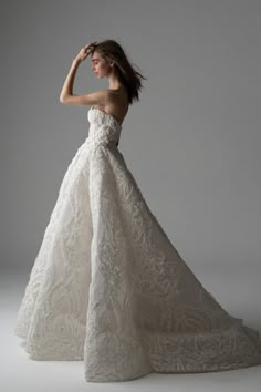 a woman in a wedding dress posing for the camera with her hand on her head