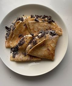 three crepes on a white plate topped with chocolate chips