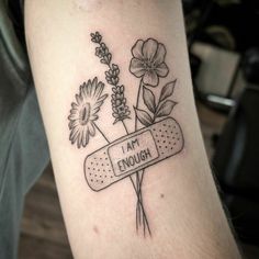 a tattoo with flowers and an inscription that says i am enough on the side of someone's arm