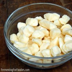 a glass bowl filled with peeled bananas on top of a wooden table