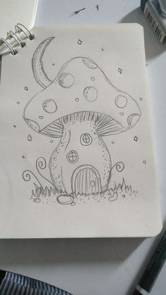 a drawing of a mushroom house on a piece of paper with pencils next to it