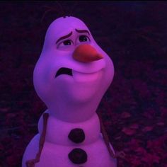 a purple snowman sitting in the grass with his eyes closed and nose wide open