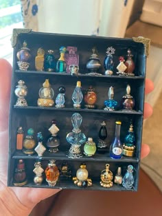 a person holding up a display case filled with lots of different types of perfume bottles