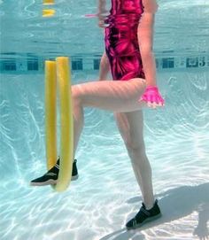 a woman in a pink swimsuit is holding a yellow pole and standing under the water