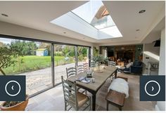 a dining room table with chairs and a skylight in the middle of an open floor plan