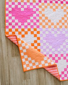 an orange and pink quilt on top of a wooden table