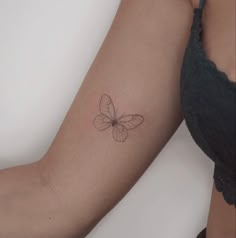 a woman's arm with a small butterfly tattoo on the left side of her arm