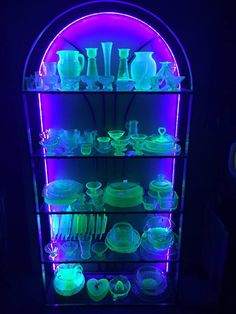 a lighted display case filled with lots of glassware and plates in blue light,