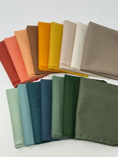 six different colors of napkins on a white surface with one folded in the middle