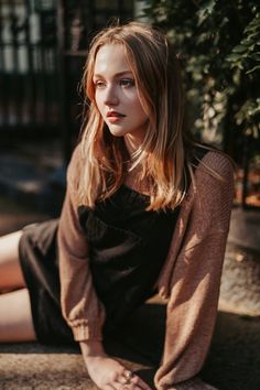 a woman sitting on the ground with her legs crossed and looking off to the side