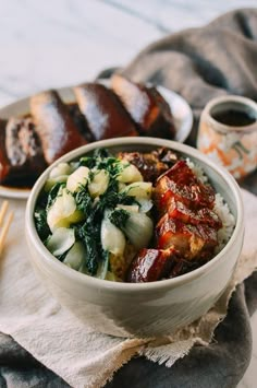 a bowl filled with meat and vegetables on top of a table next to chopsticks