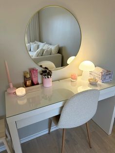 a white desk topped with a mirror next to a chair and table covered in candles