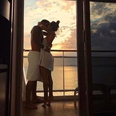 a man and woman kissing on the deck of a cruise ship at sunset or sunrise