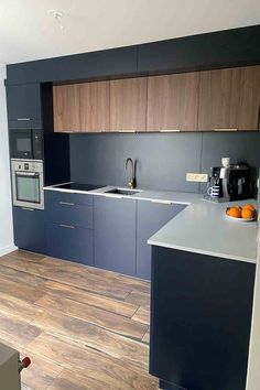 an empty kitchen with wood floors and gray cabinetry on the wall, along with a coffee maker