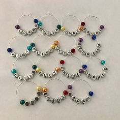 wine glass charms with the word love spelled in silver letters and colored beads are arranged on a white surface