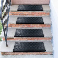 three black doormats on the steps leading up to a house