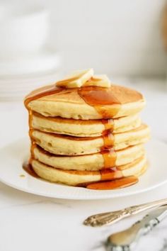 a stack of pancakes covered in syrup on a white plate