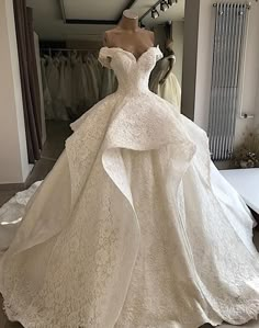 a white wedding dress is on display in a room with other dresses and accessories around it