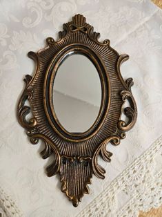 a mirror sitting on top of a table next to a white lace covered table cloth