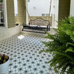 a black and white porch swing sitting on top of a tiled floor next to a potted plant