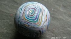 a marble ball sitting on top of a cement floor covered in multicolored swirls