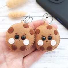 two brown teddy bear earrings with white polka dots on them sitting in front of a cell phone