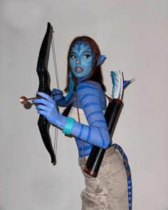 a woman with blue makeup holding a bow and arrow