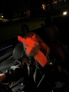 a person in a car driving at night with their hand on the steering wheel,