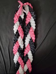 two pink and white braids on a black surface with one knot tied in the middle