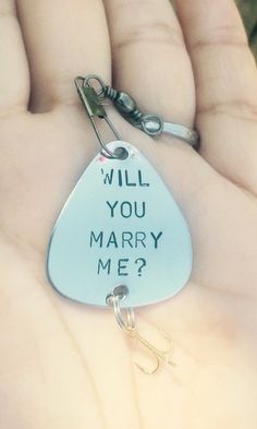 a hand holding a keychain that says will you marry me?