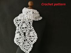 a white crocheted scarf hanging on a black mannequin