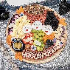 a platter filled with cheeses, crackers and grapes