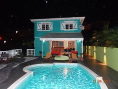 a house with a swimming pool in the middle of it at night, lit up by lights