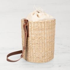 a wicker bag sitting on top of a white marble counter next to a brown leather strap