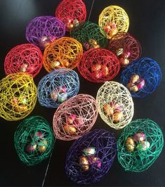 colorful string wrapped ornaments are arranged on a black surface with lights in the middle and small balls around them